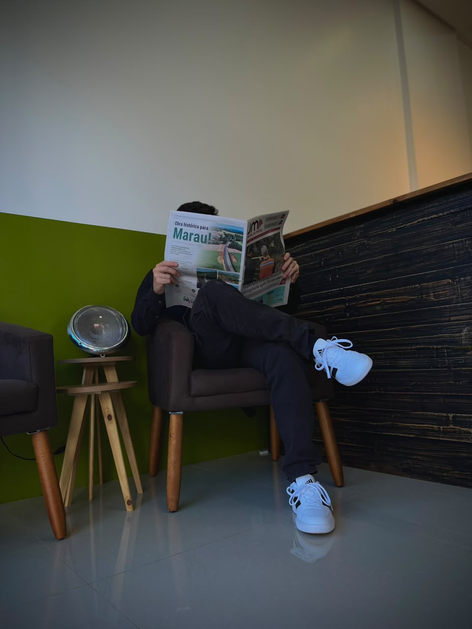 Recepção da Tratto Barbearia com poltronas, mesa lateral e parede verde oliva