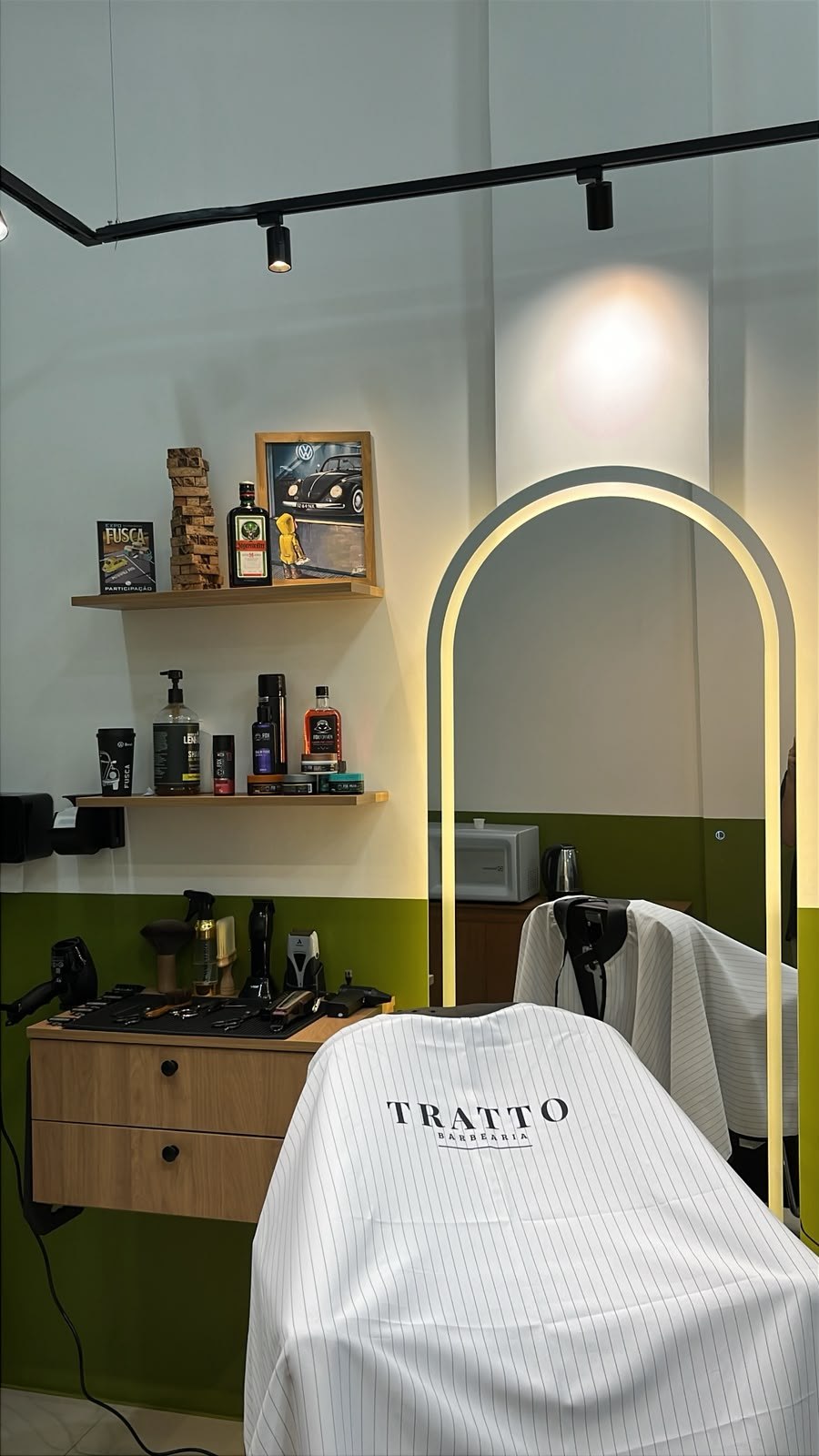 Cadeira da Tratto Barbearia diante do espelho iluminado e da bancada de trabalho