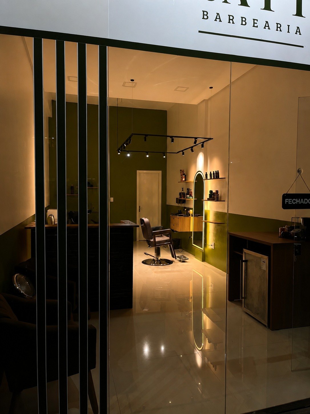 Entrada da Tratto Barbearia vista pela fachada, com o interior iluminado e o vidro sem cartaz