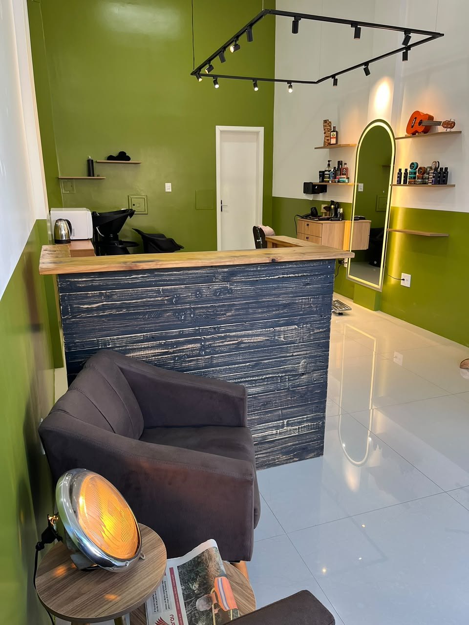 Recepção real da Tratto Barbearia com espelho iluminado e detalhes verde oliva